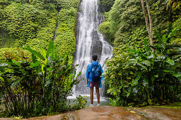 istock Rear View Of Man Standing Against Waterfall In Forest 2227884486