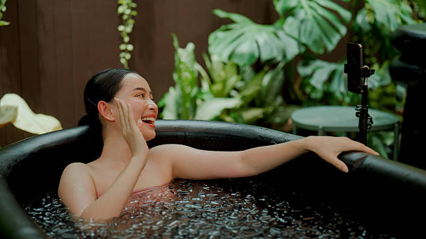 istock Young Asian woman waving to phone while live-streaming herself ice-bathing. 2227885146