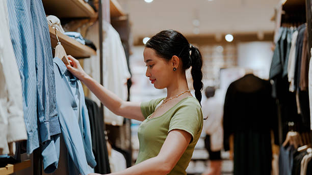 istock Young Asian woman testing clothes size while shopping at a boutique. 2227885491