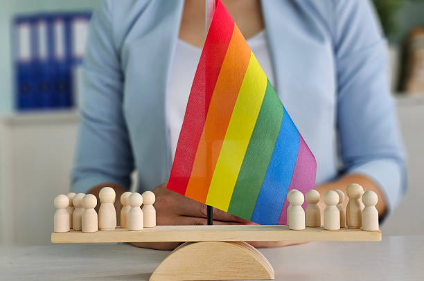 istock A row of small wooden figures stands before a bright rainbow flag, representing unity and support for the LGBT community 2227886489