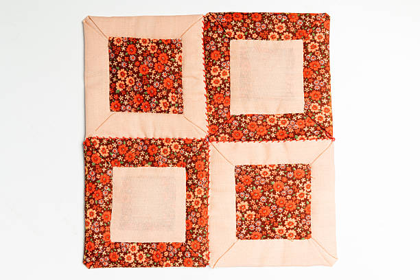 Top-down view of a quilted textile design composed of four square fabric patches in alternating floral and solid peach patterns. The stitching and design emphasize handcrafted sewing techniques, ideal for themes of DIY, quilting, home decor, or traditional crafts.