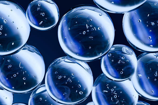 istock Transparent blue bubbles with light reflections and small air particles suspended in a dark background. Abstract 3D illustration ideal for science, skincare, or clean technology concepts. 2227888428