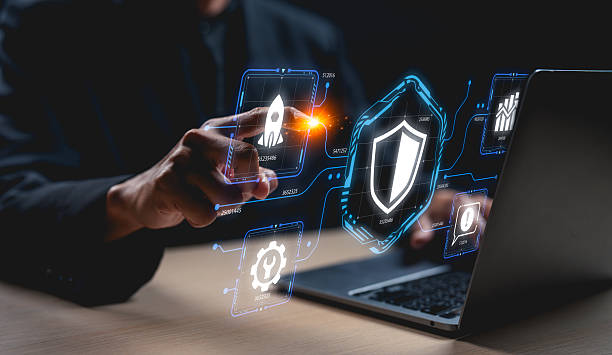 A person interacts with digital security icons on a laptop, highlighting cybersecurity and technology themes in a modern workspace.