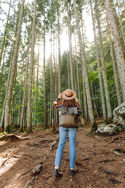 istock A young woman with a backpack and a hat walks along a rocky path in a dense forest. 2227892183