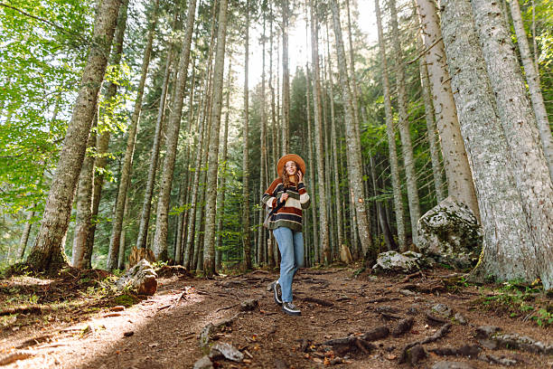 istock A young woman with a backpack and a hat walks along a rocky path in a dense forest. 2227892184