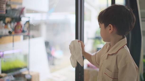 istock Little Asian Boy Assisting Dad by Cleaning Windows. 4k 2227892312