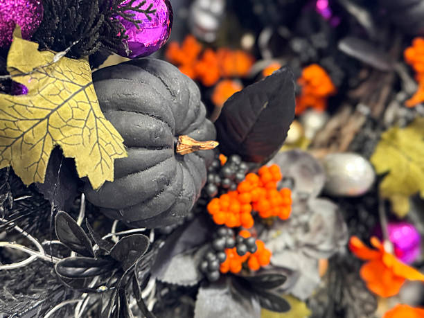 istock Full frame image of Halloween party decoration display wreath, black and silver grey artificial foliage, fake orange berries, black plastic pumpkins, silver artificial twigs, purple baubles, orange flower heads, Halloween background, focus on foreground 2227895096