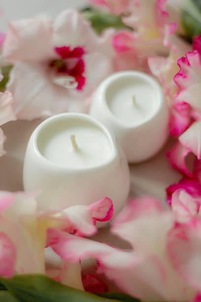 istock White ceramic candles on a soft surface with blurred pink flowers in the background. Minimalist spa composition for relaxation, wellness, aromatherapy, and home decor concepts. 2227895317