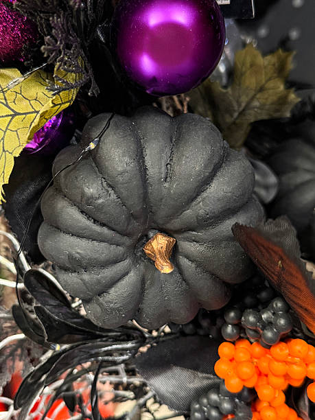 istock Full frame image of Halloween party decoration display wreath, black and silver grey artificial foliage, fake orange berries, black plastic pumpkins, silver artificial twigs, purple baubles, Halloween background, focus on foreground 2227895337