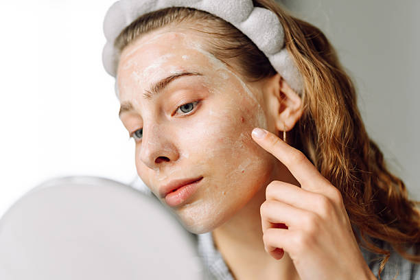 istock A young woman looking at a small mirror in a cozy room. 2227896247