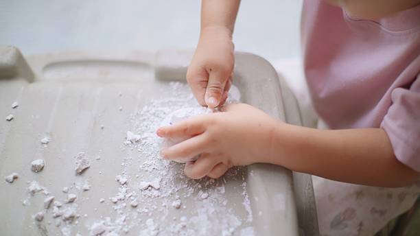 enthusiastic young Asian boy engages in a fun and educational activity, carefully excavating a toy dinosaur egg to discover the hidden dinosaur inside — combining play with learning and imagination.