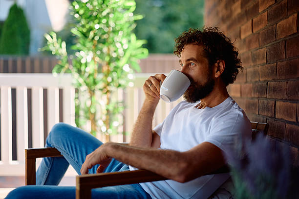 istock Mid adult man drinking coffee while relaxing on the porch. 2227901078