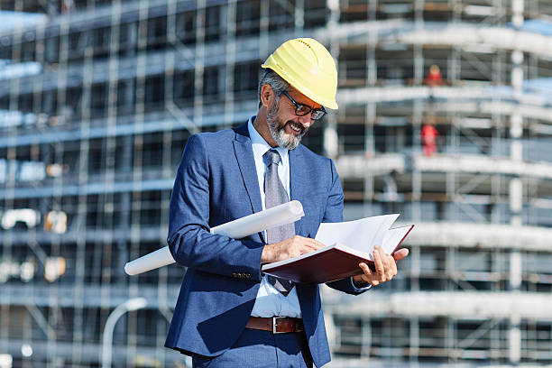 istock senior businessman architect helmet construction site building architecture writing notebook protective workwear blueprint plan 2227902398