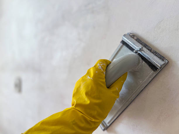 istock Construction worker sanding wall with sandpaper holder and wearing yellow gloves 2227903964