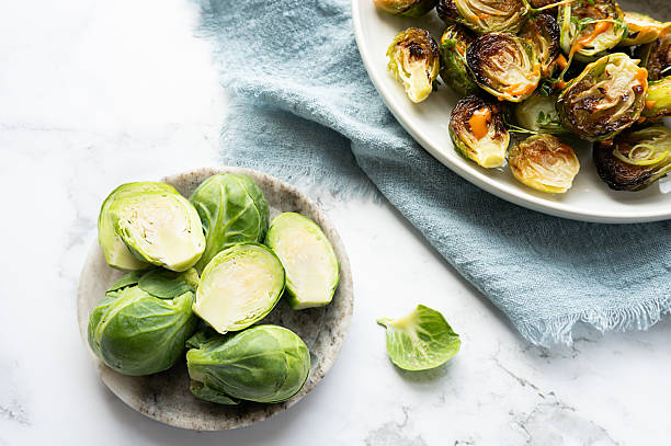 istock Healthy lifestyle concept with freshly roasted Brussels sprouts next to raw halves. 2227904607