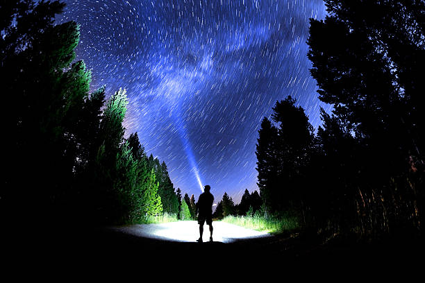 istock Man Standing in Dark Stars with Flashlight Forest Night Sky Milky Way Star Circles 2227907425