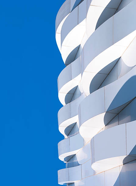 istock Building exterior modern architecture design, 3d dimension curve pattern of geometric white aluminium composite tile wall decoration against blue sky vertical background 2227921421