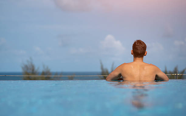 istock Tourist relaxing in infinity pool overlooking tropical ocean 2227924342
