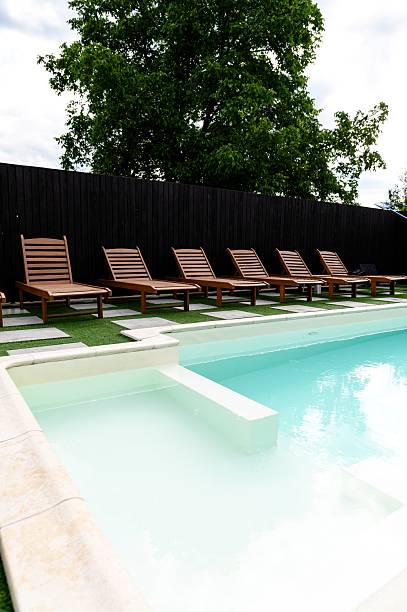 istock Calm afternoon by the poolside with lounge chairs and lush greenery in a private setting 2227928074