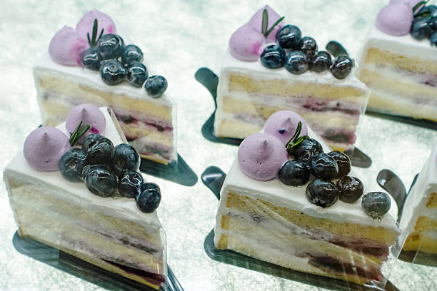 istock Delicious layered cake slices topped with blueberries and cream on a reflective surface 2227929833
