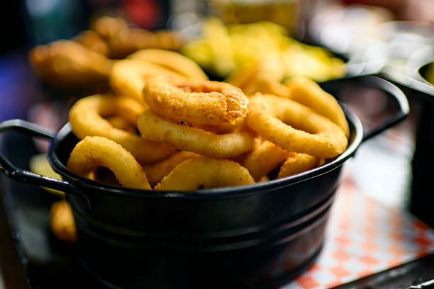 Close up shot of dishes with onion rings, chicken wings, potatoes, deep dish on a table in a pub. Outdoor eating, nightlife, restaurants, socialising.