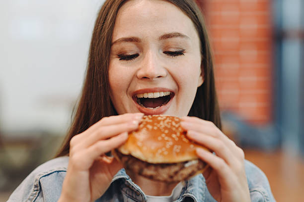 istock hamburger in hands, closeup view, young woman eats hamburger 2227933922