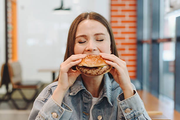 istock hamburger in hands, closeup view, young woman eats hamburger 2227933926