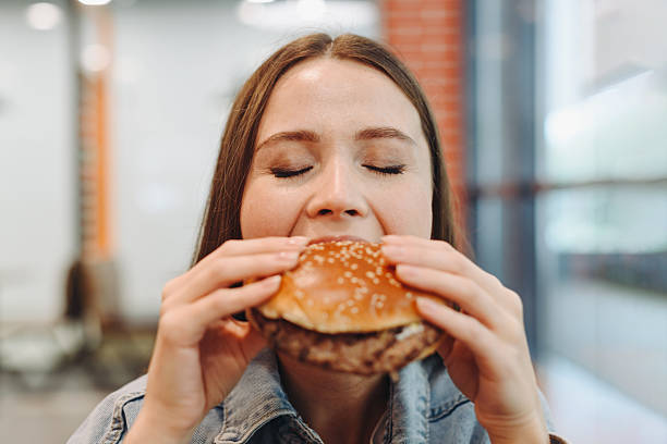 istock hamburger in hands, closeup view, young woman eats hamburger 2227933934