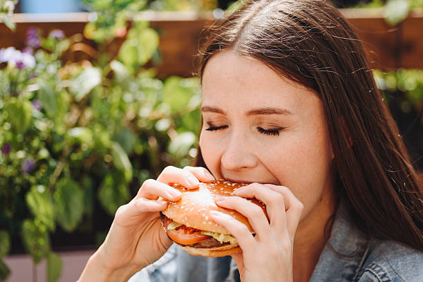 istock hamburger in hands, closeup view, young woman eats hamburger 2227933936