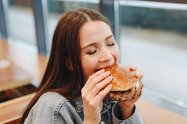istock hamburger in hands, closeup view, young woman eats hamburger 2227933939