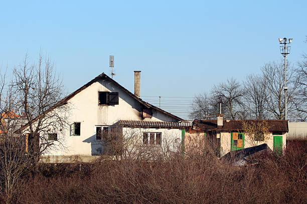 istock Aged residential house with green window shutters and bare trees 2227934316