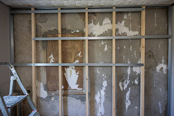 istock Metal and wood studs are attached to a concrete wall to create a frame for a partition during a home renovation project, with remnants of old wallpaper visible. A frame for attaching drywall sheets. 2227935867