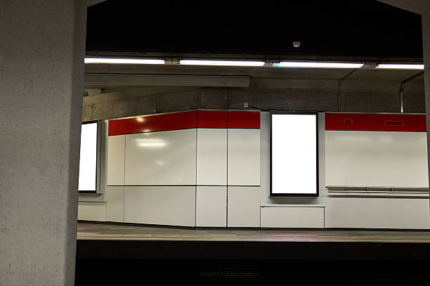 Empty advertising billboard on a subway station wall, illuminating the platform and waiting area