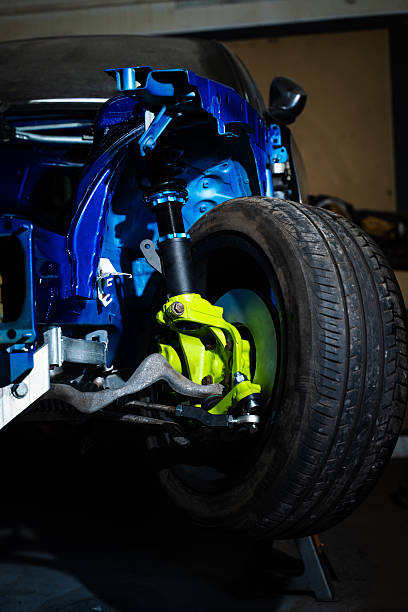istock Installing rear suspension arms under the chassis. Rear Suspension Installation Under Chassis for Drift Car Build. Technician tightens arms and subframe connections beneath the chassis. 2227939518