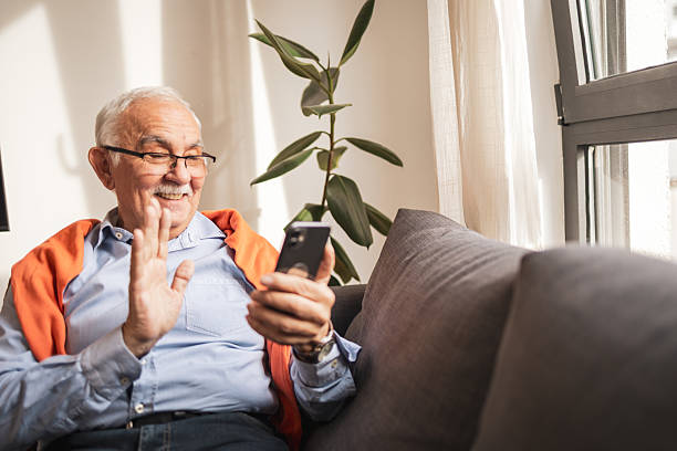 istock Senior man video chatting on smartphone while relaxing on his sofa indoors 2227948110