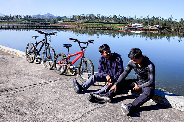 Two Friends Sitting Beside Their Bikes, Chatting And Relaxing With a Countryside View