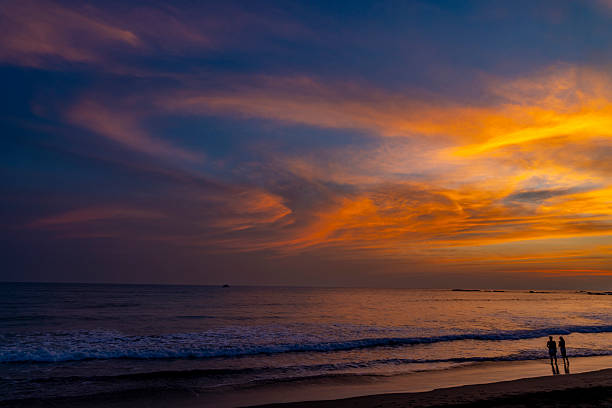 Couple walking along the beach enjoying a beautiful and colorful sunset in Jaco, Costa Rica