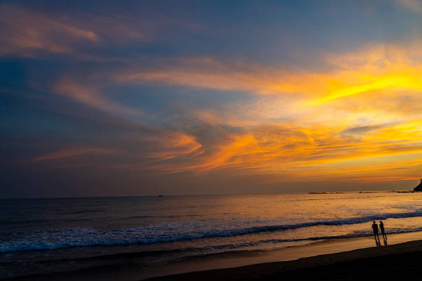 Couple walking along the beach enjoying a beautiful and colorful sunset in Jaco, Costa Rica