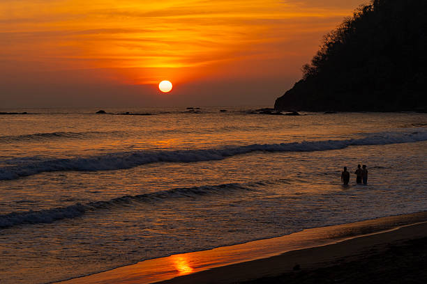 Group of people on the beach enjoying a beautiful and colorful sunset in Jaco, Costa Rica