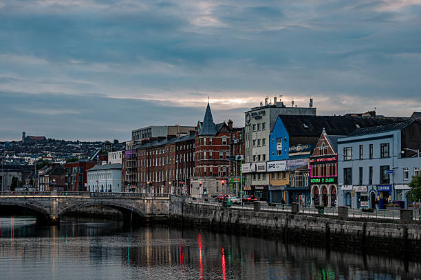 July 24, 2025 Cork, Ireland A peaceful and tranquil evening view showcases colorful buildings lining a river beneath a beautifully cloudy sky