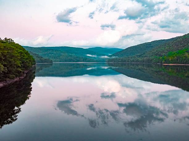 istock Calm lake with dramatic, purple sky, surrounded by forested hills 2227962545