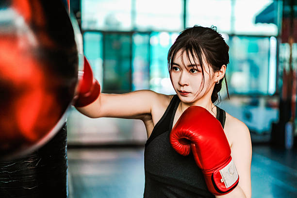 istock Focused female boxer practicing punches with gloves at gym punching sandbag. 2227967032
