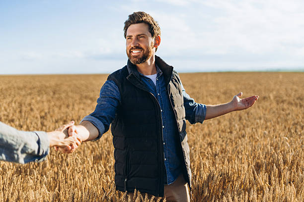 istock Farmer shaking hands and showing his wheat field with pride 2227972309