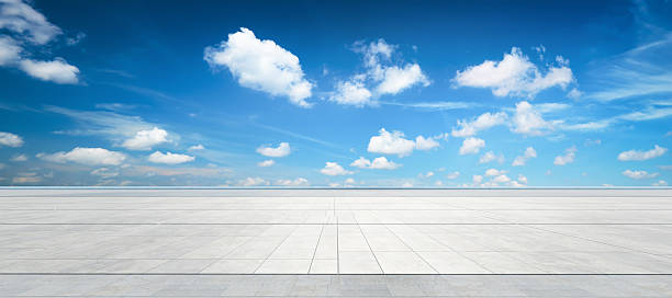 istock Expansive concrete ground meeting a vast blue sky with fluffy white clouds 2227976167