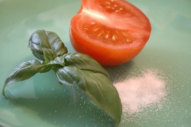 One red half tomato with basil and salt on blue plate