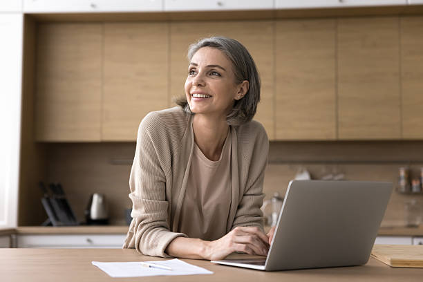 istock Mature businesswoman working at home looking aside from notebook screen 2227976389