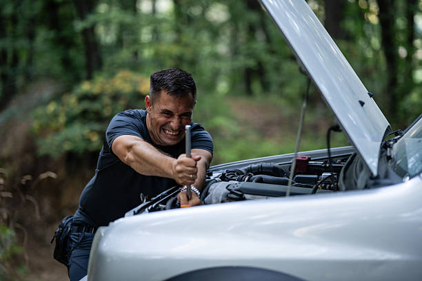 istock Frustrated driver struggling to repair broken down car in forest 2227976593