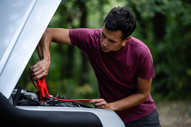 istock Man charging car battery with jumper cables in forest roadside assistance 2227976941