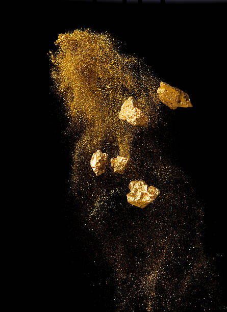 Explosion metallic gold glitter sparkle and gold nuggets on black background.