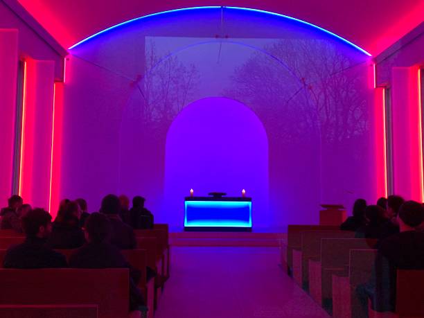 Altar of the Blessed Virgin Mary with Malden Jesus and burning candles against the background of blue light from LED lamps inside the church, Nuremberg, Germany.